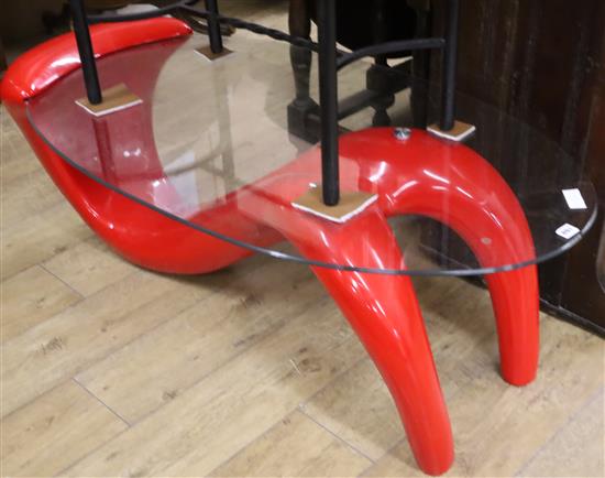 A contemporary red composition oval glass top coffee table W.124cm